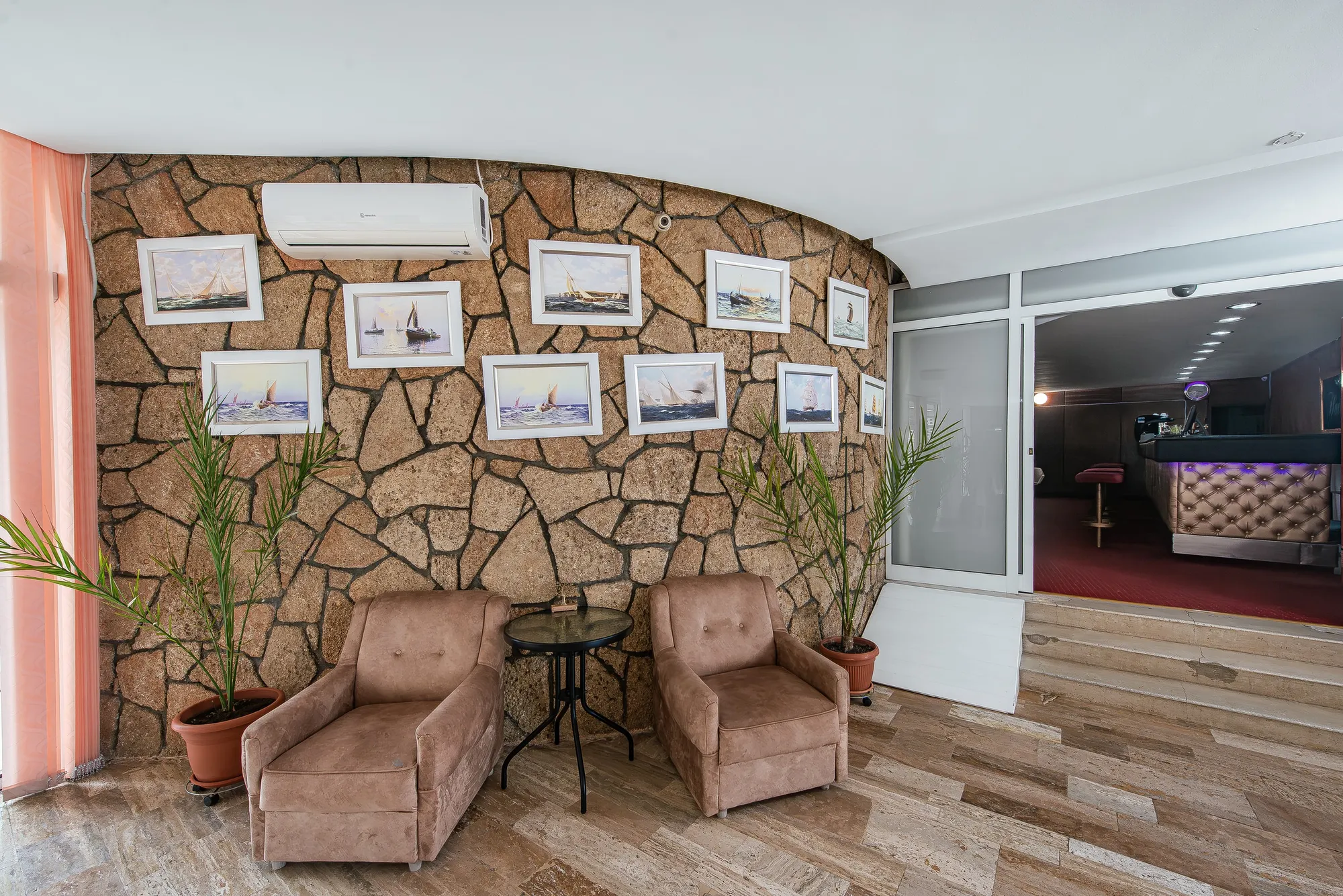Colțul de lounge cu fotolii și perete de piatră decorat