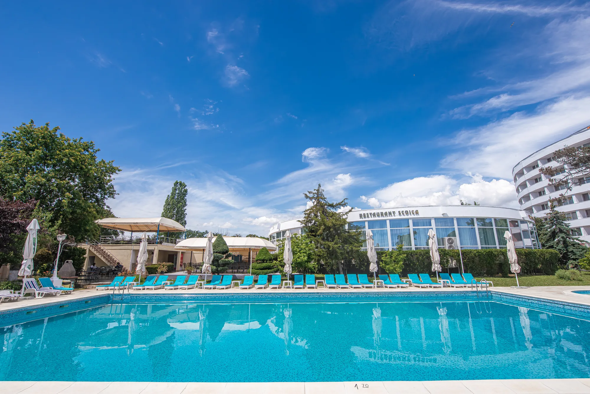 Piscina principală și șezlongurile, cu restaurantul în fundal