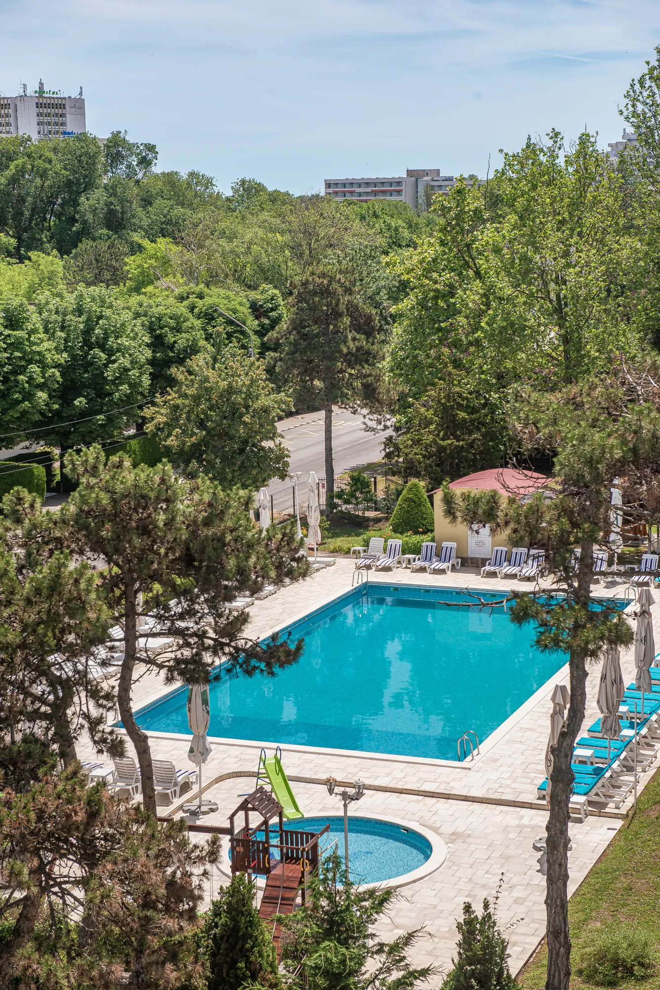 Zona piscinelor și locul de joacă, văzute de sus, printre pini