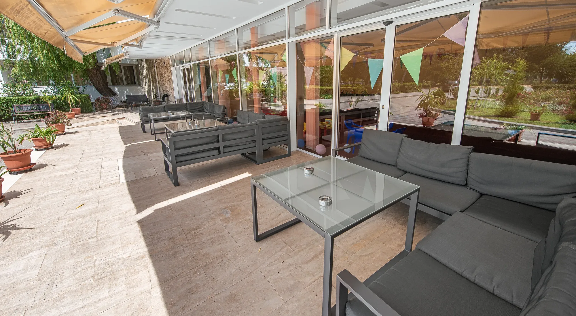 Terasa-lounge acoperită a hotelului, deschisă spre grădină